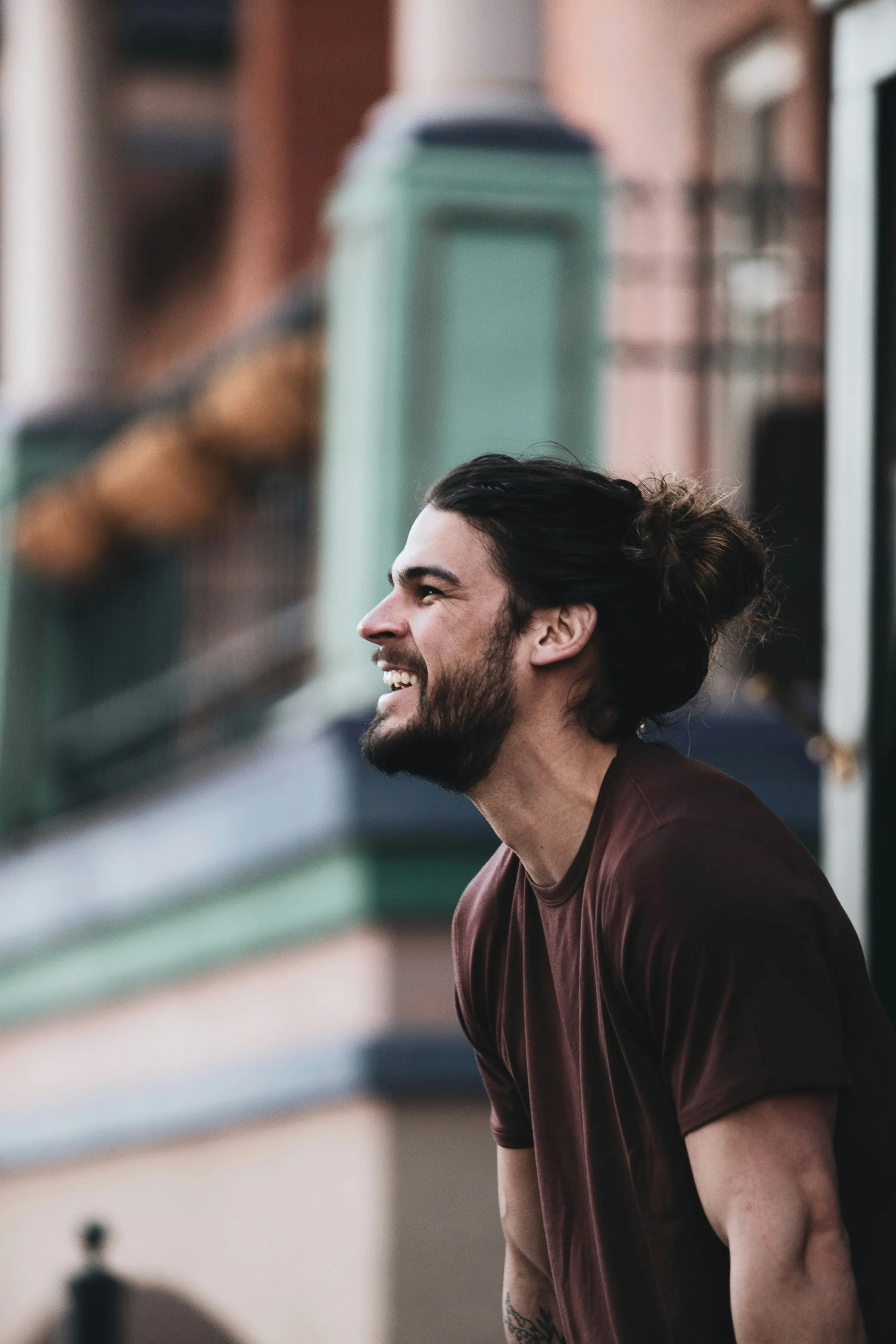 Confident man in maroon shirt seated outdoors in urban setting