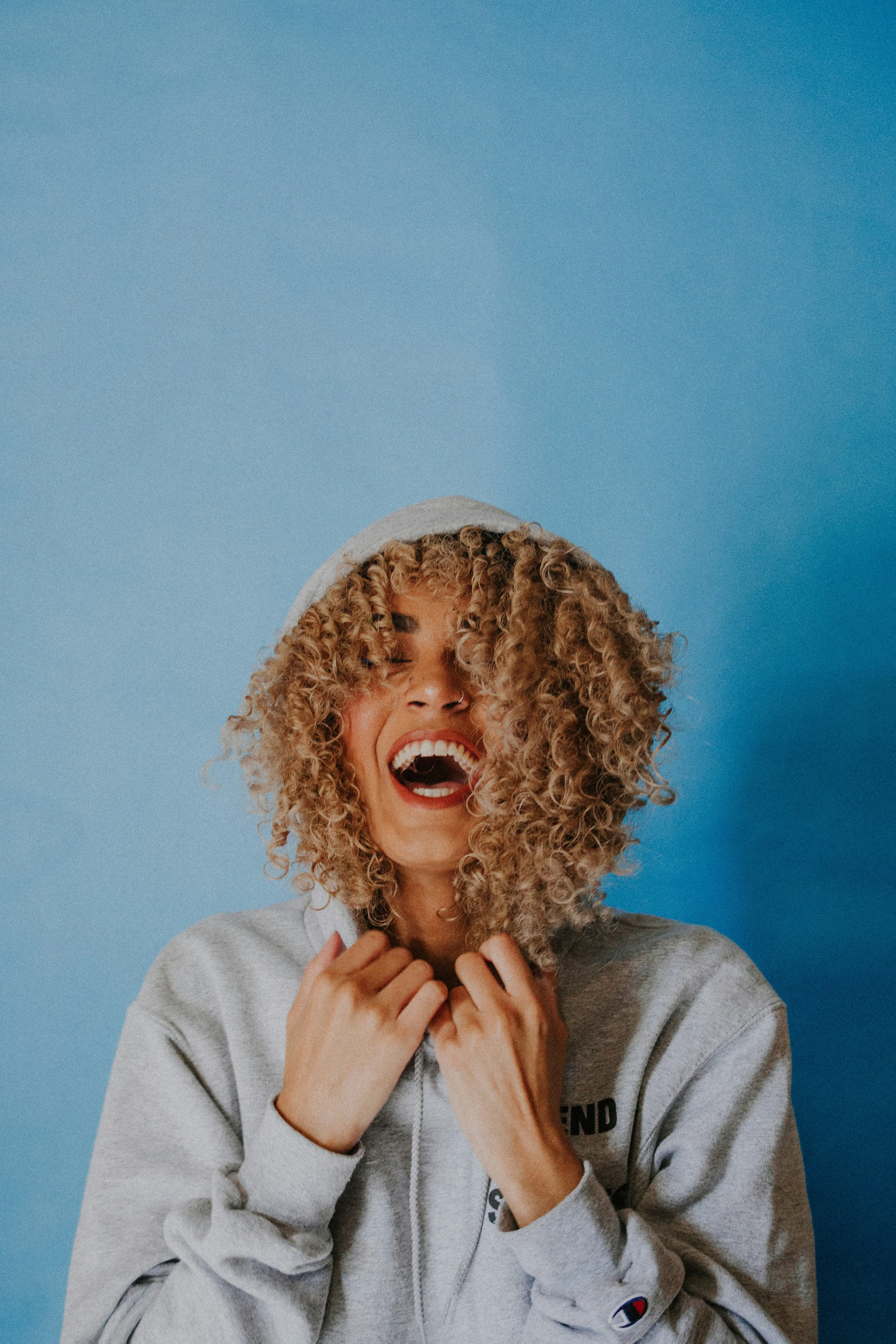 Close-up portrait of woman smiling behind hoodie