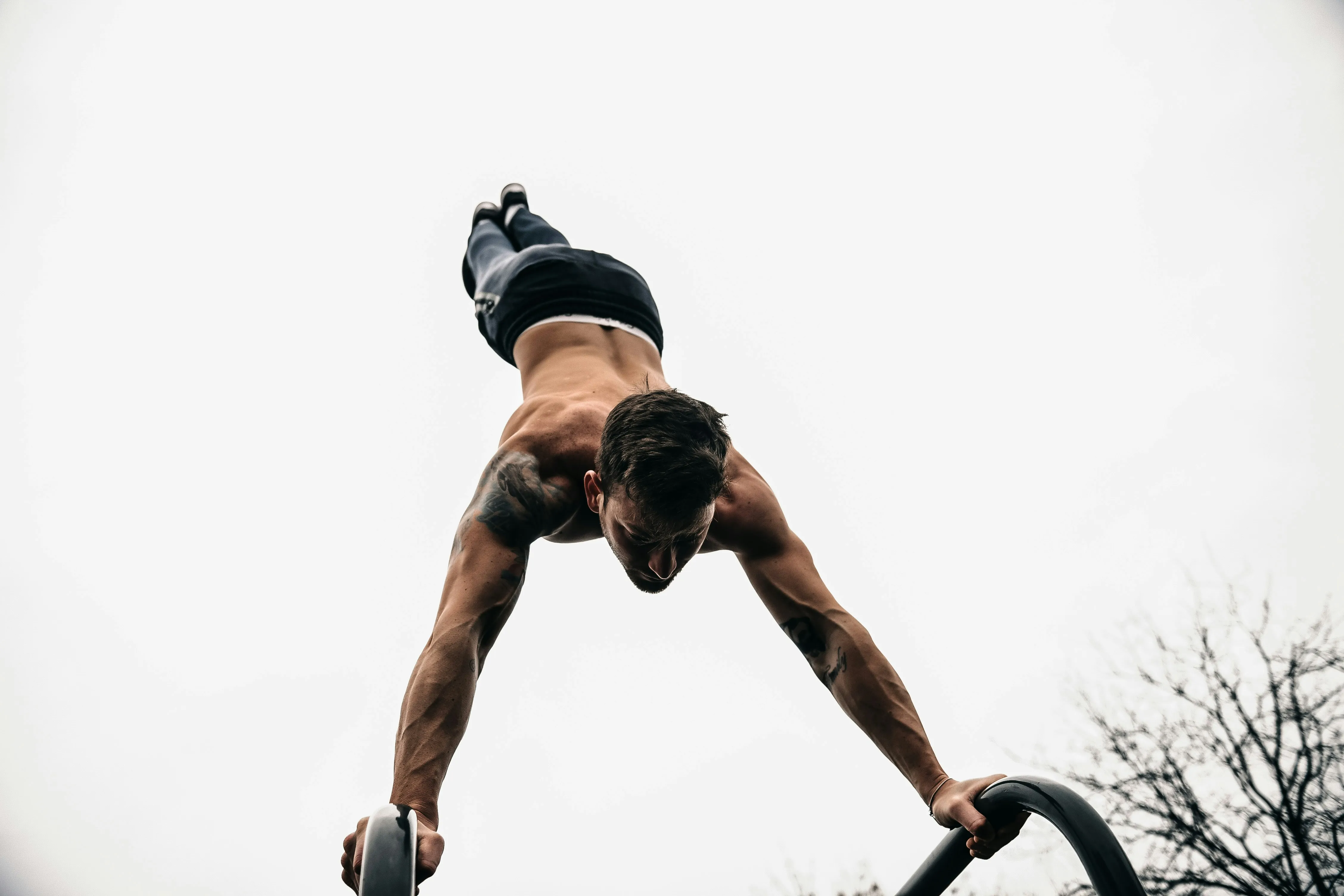 Shirtless man performing an inverted workout pose